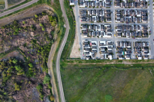 Aerial view showing contrast between a housing development and surrounding natural green space, highlighting urban planning and environmental sustainability.