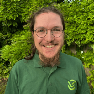 Introducing Jude - Little Green Consulting Consultant Jude stood smiling in front of a green background