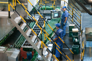 Factory workers monitoring an automated bottling production line in a beverage manufacturing facility